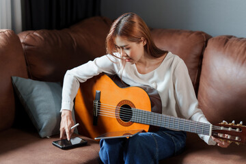 A beginner woman playing acoustic guitar lesson