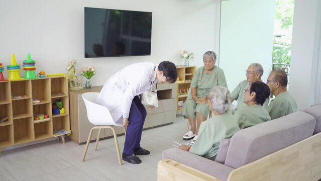An Asian doctor talking to a group of old elderly patient or pensioner people smiling, relaxing, having fun together in nursing home. Senior lifestyle activity recreation. Retirement. Health care