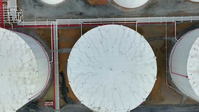 Top down aerial of oil gas bulk tanks at refinery. Pipeline connects storage silos. Birds eye view.