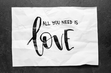 All you need is love. Lettering on crumpled white paper. Handwritten text. Inspirational quotes.