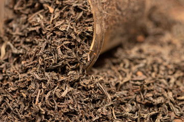 Large-leaf black tea in a glass and scattered on the table. Close-up of the surface texture