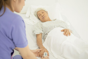 Obraz premium Nurse uses pulse oximeter to measure elderly patient's blood oxygen satuation at home health care