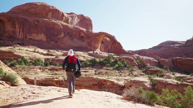 Hiker Walking towards Corona Arch - Moab, United States