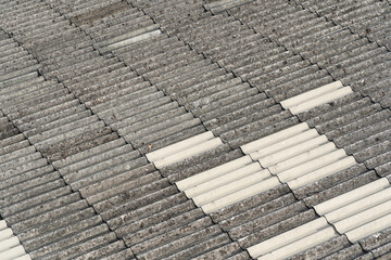 Old double corrugated roofing covered with dry moss and rust, White grey gypsum tile with stain on surface. Asbestos corrugated roof covering. 