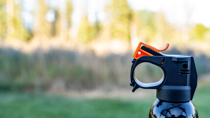 Aerosol trigger of a can of bear spray in an outdoor setting