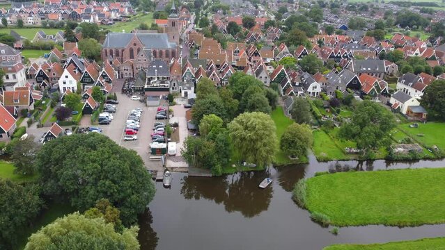 Side pan aerial view of a small Dutch village with a large church surrounded by farms and canals.
