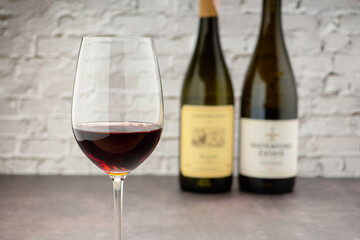 Red wine glass and bottles with white brick wall background