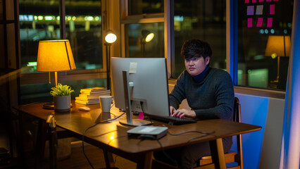 Asia freelance man focus work on computer in living room at home overtime at night.man at home and...
