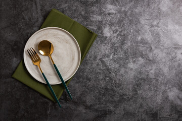 Trendy minimal tableware setting with the gray plate and golden cutlery