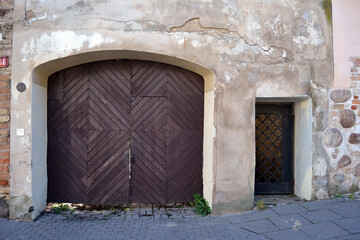 Obraz premium Antique wooden gate in a stone wall. Fragment of the facade.