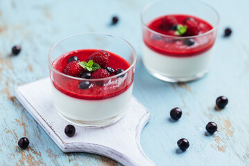 Panna cotta dessert with sauce from berries. Cherries, raspberries and blueberry as decoration....
