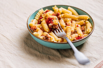 Bolognese pasta in blue plate on bright background. Traditional Italian dish