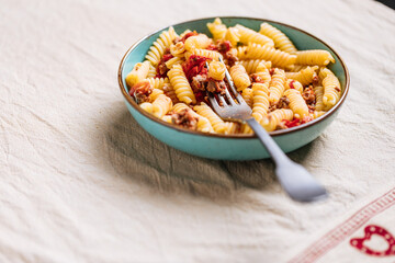 Bolognese pasta in blue plate on bright background. Traditional Italian dish