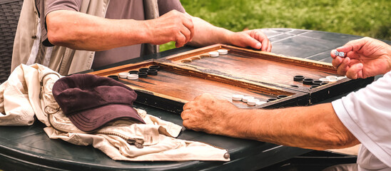 Board game of backgammon.Two old adult men playing backgammon in the street,hobby