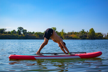 yoga on the sap board. the guy in the dog face down pose. water sports.