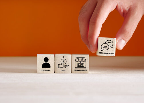 Hand puts the wooden cubes with the 4c of marketing mix consumer, cost, convenience, and communication.