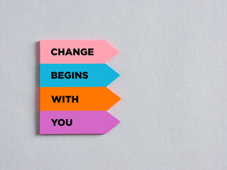 Colorful arrow shaped stickers with the message change begins with you.