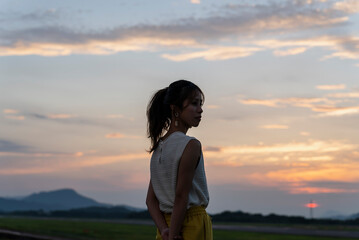 夕暮れの飛行場を眺める女性