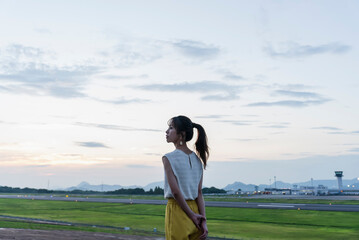 夕暮れの飛行場を眺める女性