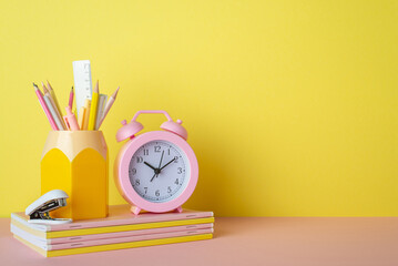 Back to school concept. Photo of school supplies on pink desk pen holder with pencils ruler alarm...