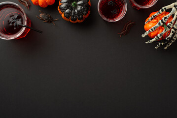 Halloween concept. Top view photo of blood punch in glasses with floating spiders and straw...