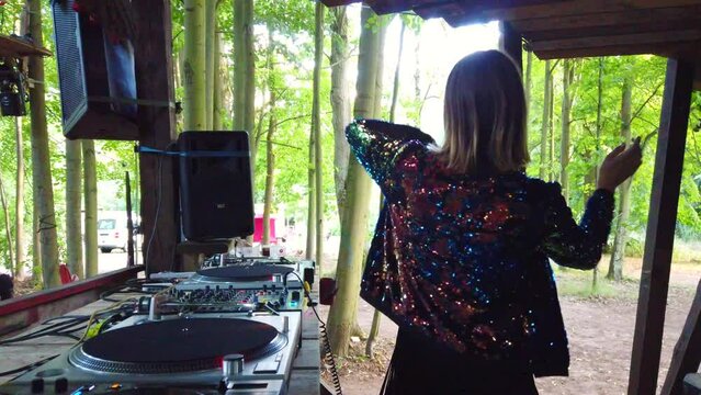 Woman dancing lasciviously and puts her headphones on.
Female Dj at work on a music festival rote dichte in the woods play techno. Shoot on a underground music party in forest by Philipp Marnitz