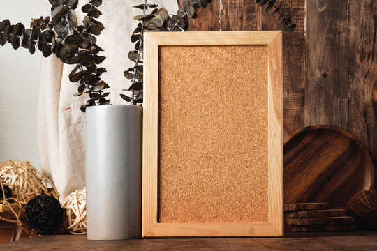 blank corkboard with kitchenware on wood table with sunlight