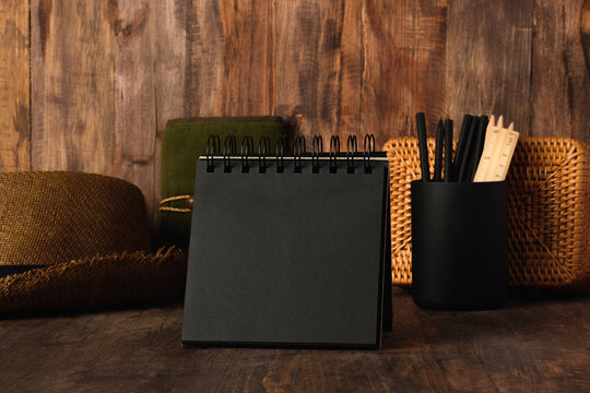 blank black sprial notebook diary with travel stuff on wood table