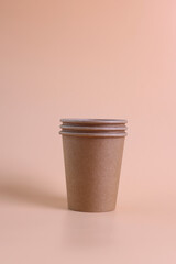 A stack of disposable paper coffee cups on pastel background. Eco-friendly hot drink containers top view.
