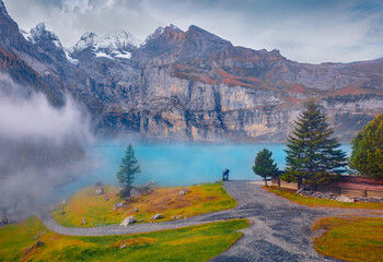 Snowy peaks in the morning mist. Foggy autumn scene of unique Oeschinensee Lake. Fantastic outdoors...
