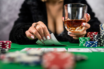 sexy woman with poker cards and chips in hands playing poker at the table.