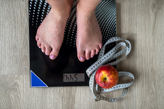 Cropped image of woman standing on scales against measuring tape and apple.