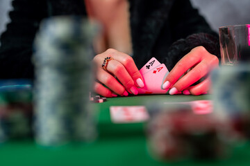 young woman is holding gambling chips and casino cards at the table in a beautiful dress.