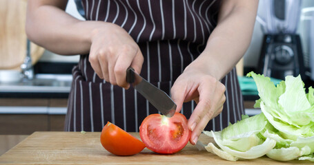 Closeup tomato sliced on a wooden chop board. Crisphead Lettuce lay next to it.