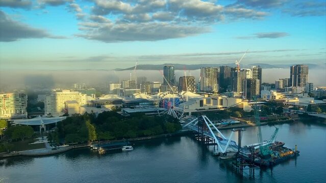 Beautiful cityscape timelapse of Brisbane South Bank with early morning rolling fog bank and commuter ferries on the river next to the contruction work on the Neville Bonner Bridge