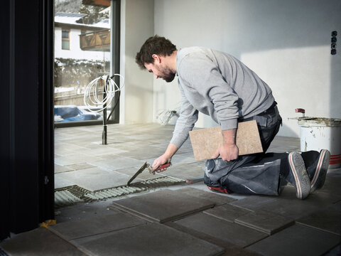 Tiler applying adhesive on floor at construction site