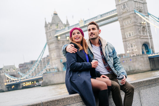 London, United Kingdom. A couple of boy and girl sitting next to Tower Bridge