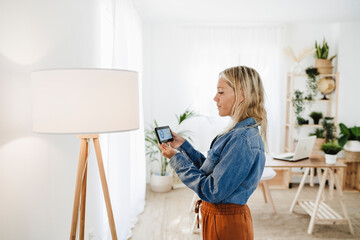 Woman checking electrical consumption of lamp at home