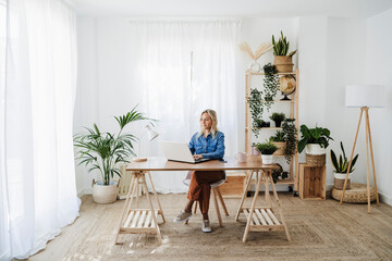 Freelancer working on laptop sitting at desk in home office