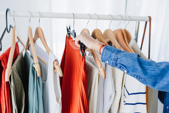 Hand of businesswoman arranging clothes on rack