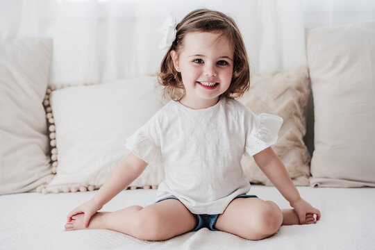 Happy cute little girl sitting on sofa at home