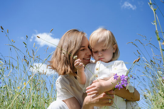 Smiling mother embracing cute daughter on field