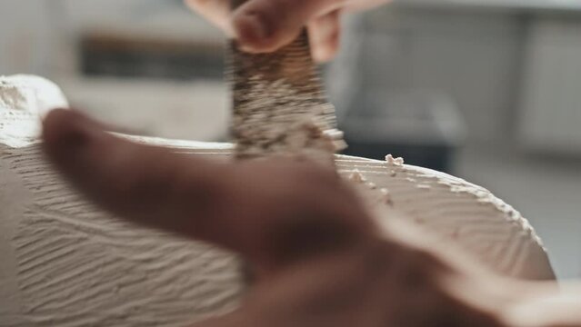 Slow motion of unrecognizable prosthetic production craftsman using perforated hand tool to remove extra plaster layer