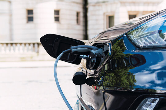 Charging cable plugged in electric car at roadside