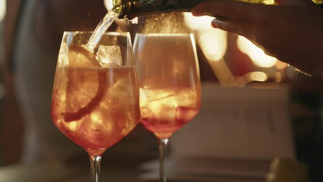 2 Drinks of Aperol getting filled  with proseco during golden hour closeup from drinks
