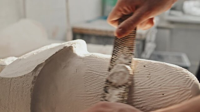 Close-up of unrecognizable man working in prosthetic production industry sculpting plaster cast for socket