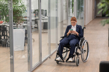 Obraz premium Caucasian woman using mobile phone in wheelchair at office. 