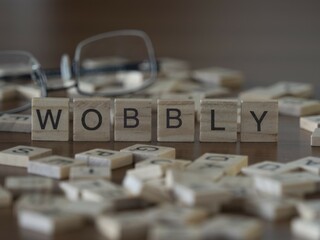Wobbly word or concept represented by wooden letter tiles on a wooden table with glasses and a book - obrazy, fototapety, plakaty