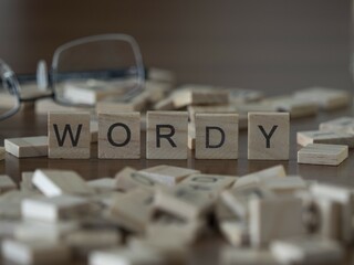 Wordy word or concept represented by wooden letter tiles on a wooden table with glasses and a book