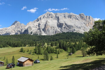 Fototapeta na wymiar Val Badia, Italy-July 17, 2022: The italian Dolomites behind the small village of Corvara in summer days with beaitiful blue sky in the background. Green nature in the middle of the rocks.
